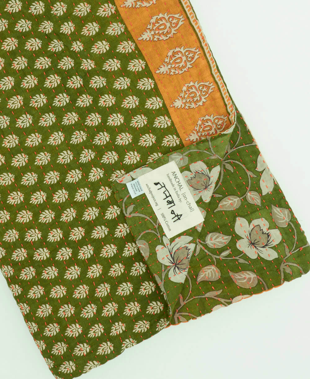 fern green & white floral kantha quilt throw with a tag featuring the hand-stitched signature of the maker