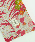 red & grey abstract kantha quilt throw with a tag featuring the hand-stitched signature of the maker