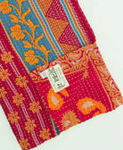 red, orange & blue stripe kantha quilt throw with a tag featuring the hand-stitched signature of the maker