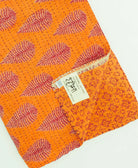 orange & red leaf kantha quilt throw with a tag featuring the hand-stitched signature of the maker