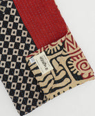 red & black kantha quilt throw with a tag featuring the hand-stitched signature of the maker