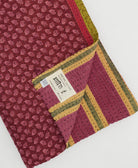 red-purple kantha quilt throw with a tag featuring the hand-stitched signature of the maker