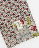 Red & green floral kantha quilt throw with a tag featuring the hand-stitched signature of the maker