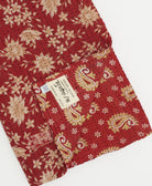 Cherry red kantha quilt throw with a tag featuring the hand-stitched signature of the maker