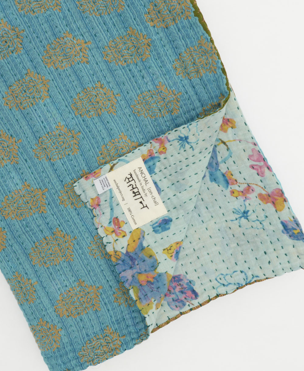 blue & brown floral kantha quilt throw with a tag featuring the hand-stitched signature of the maker