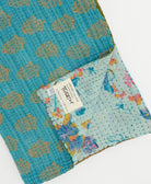 blue & brown floral kantha quilt throw with a tag featuring the hand-stitched signature of the maker