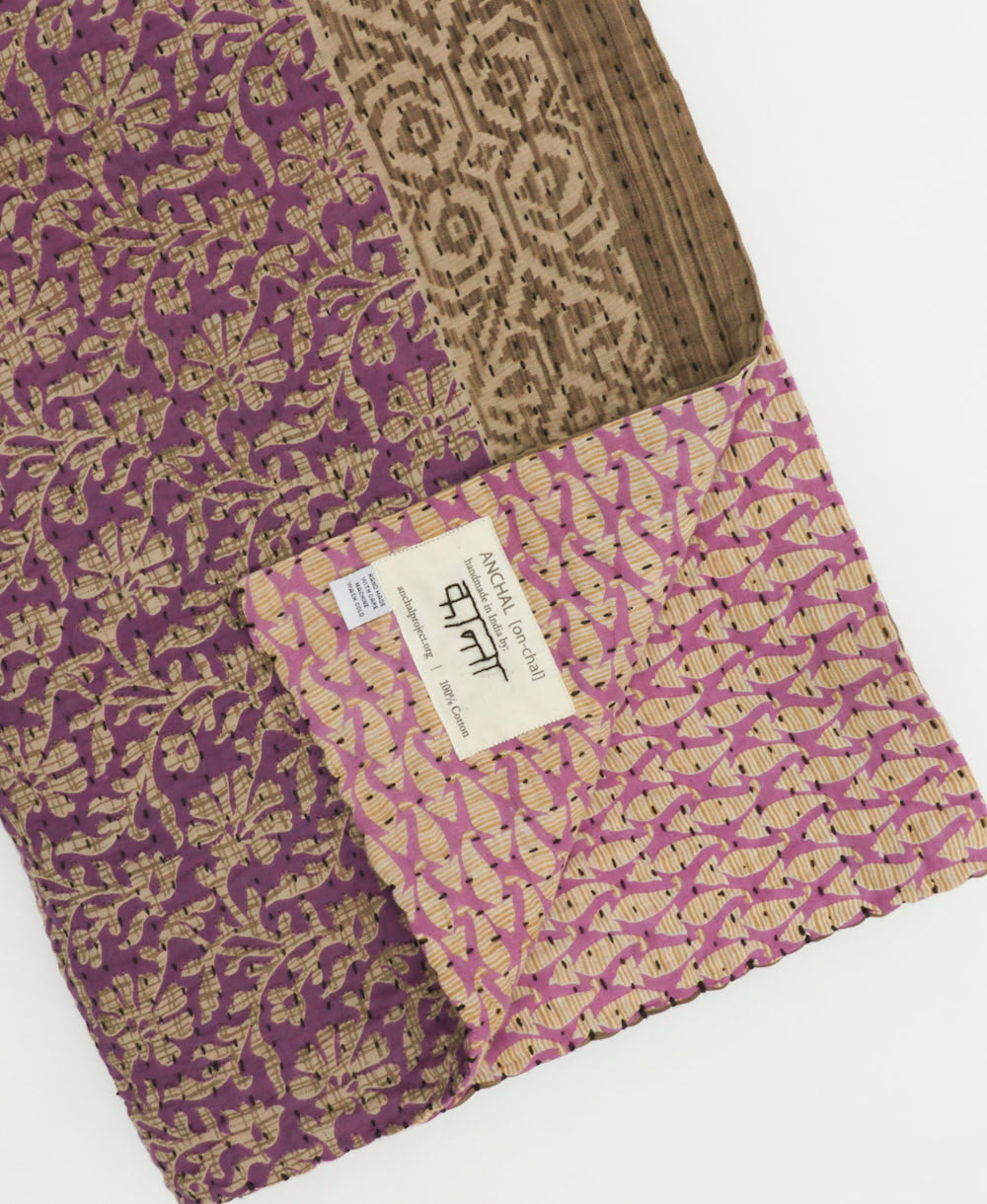 lilac purple floral kantha quilt throw with a tag featuring the hand-stitched signature of the maker