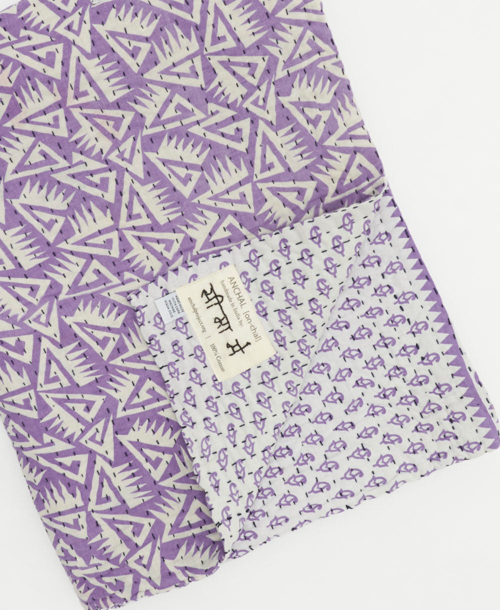 lavender floral kantha quilt throw with a tag featuring the hand-stitched signature of the maker