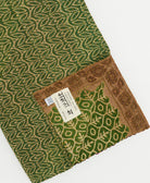 green kantha quilt throw with a tag featuring the hand-stitched signature of the maker