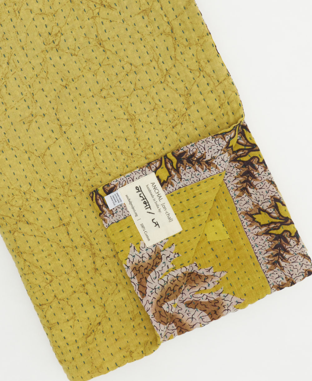 sunshine yellow kantha quilt throw with a tag featuring the hand-stitched signature of the maker