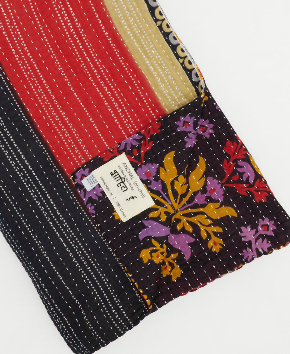 navy stripe kantha quilt throw with a tag featuring the hand-stitched signature of the maker