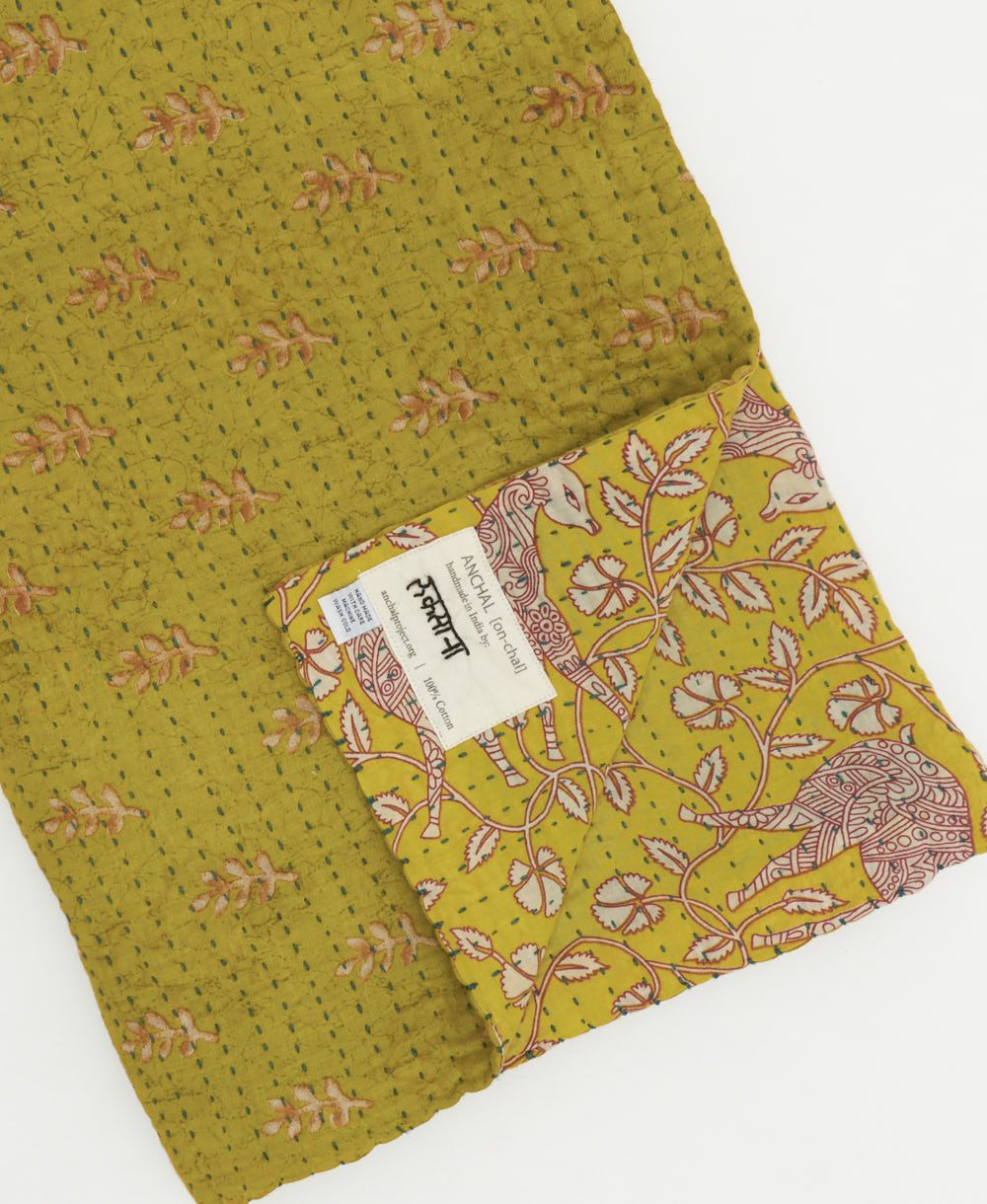 lime green kantha quilt throw with a tag featuring the hand-stitched signature of the maker