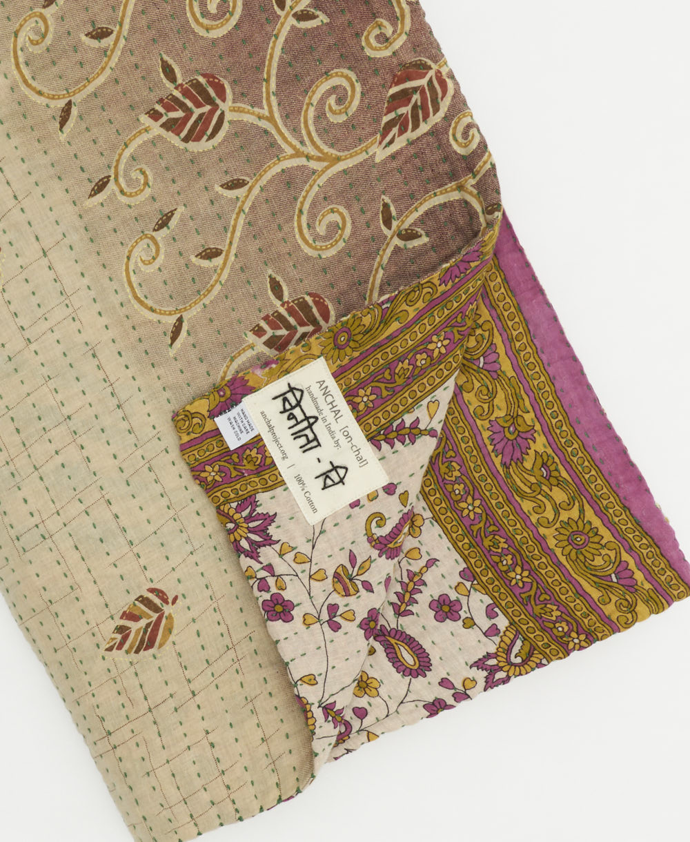 white & olive paisley kantha quilt throw with a tag featuring the hand-stitched signature of the maker