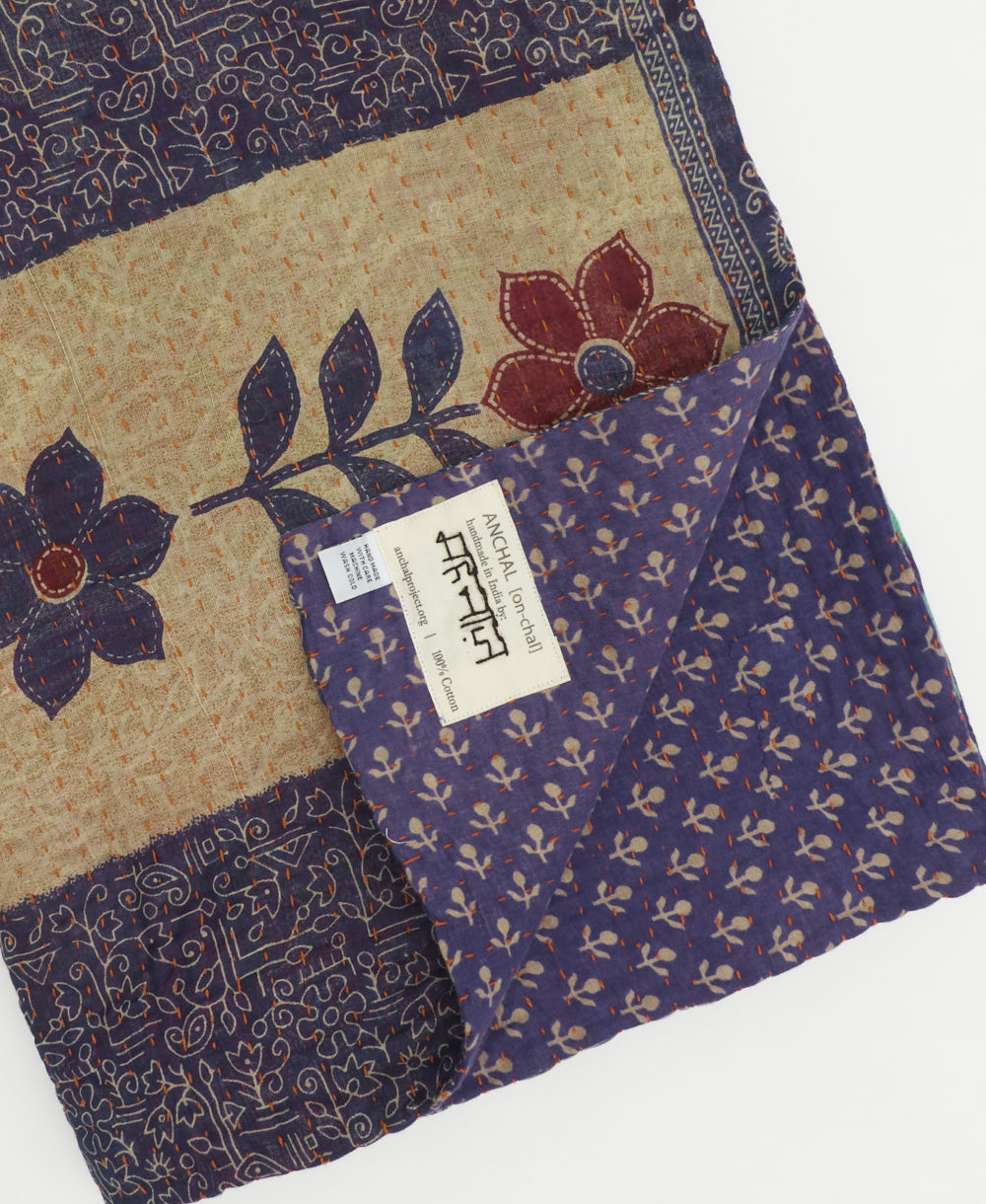 kantha quilt throw with a tag featuring the hand-stitched signature of the maker