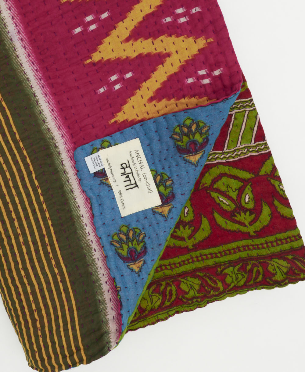 kantha quilt throw with a tag featuring the hand-stitched signature of the maker