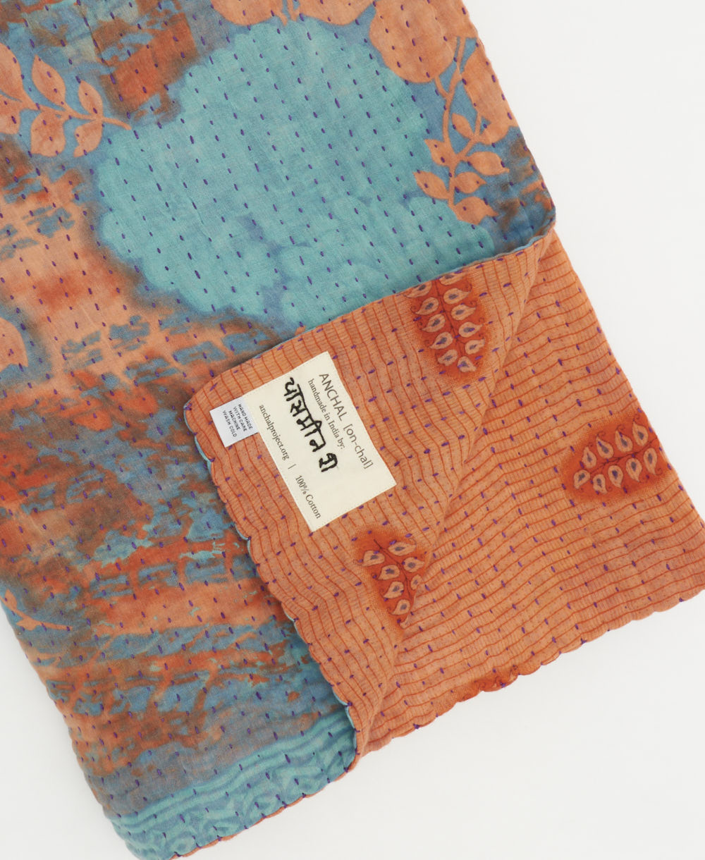 kantha quilt throw with a tag featuring the hand-stitched signature of the maker