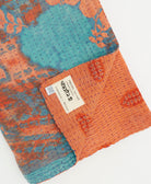 kantha quilt throw with a tag featuring the hand-stitched signature of the maker