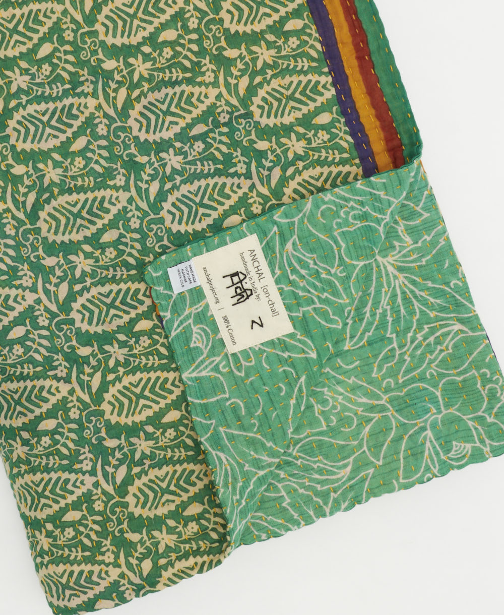 kantha quilt throw with a tag featuring the hand-stitched signature of the maker