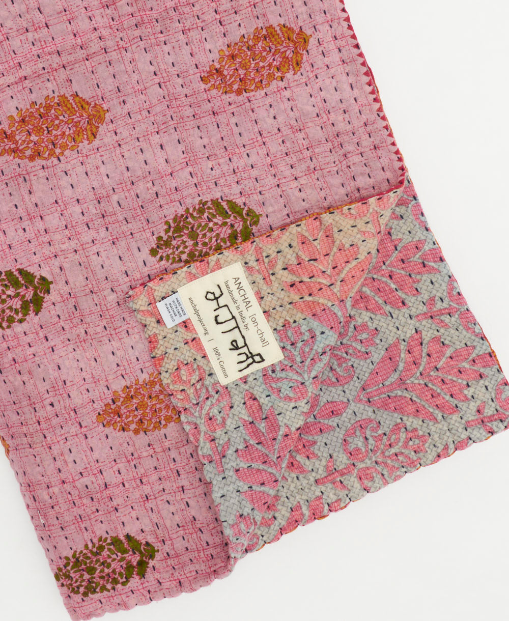 kantha quilt throw with a tag featuring the hand-stitched signature of the maker