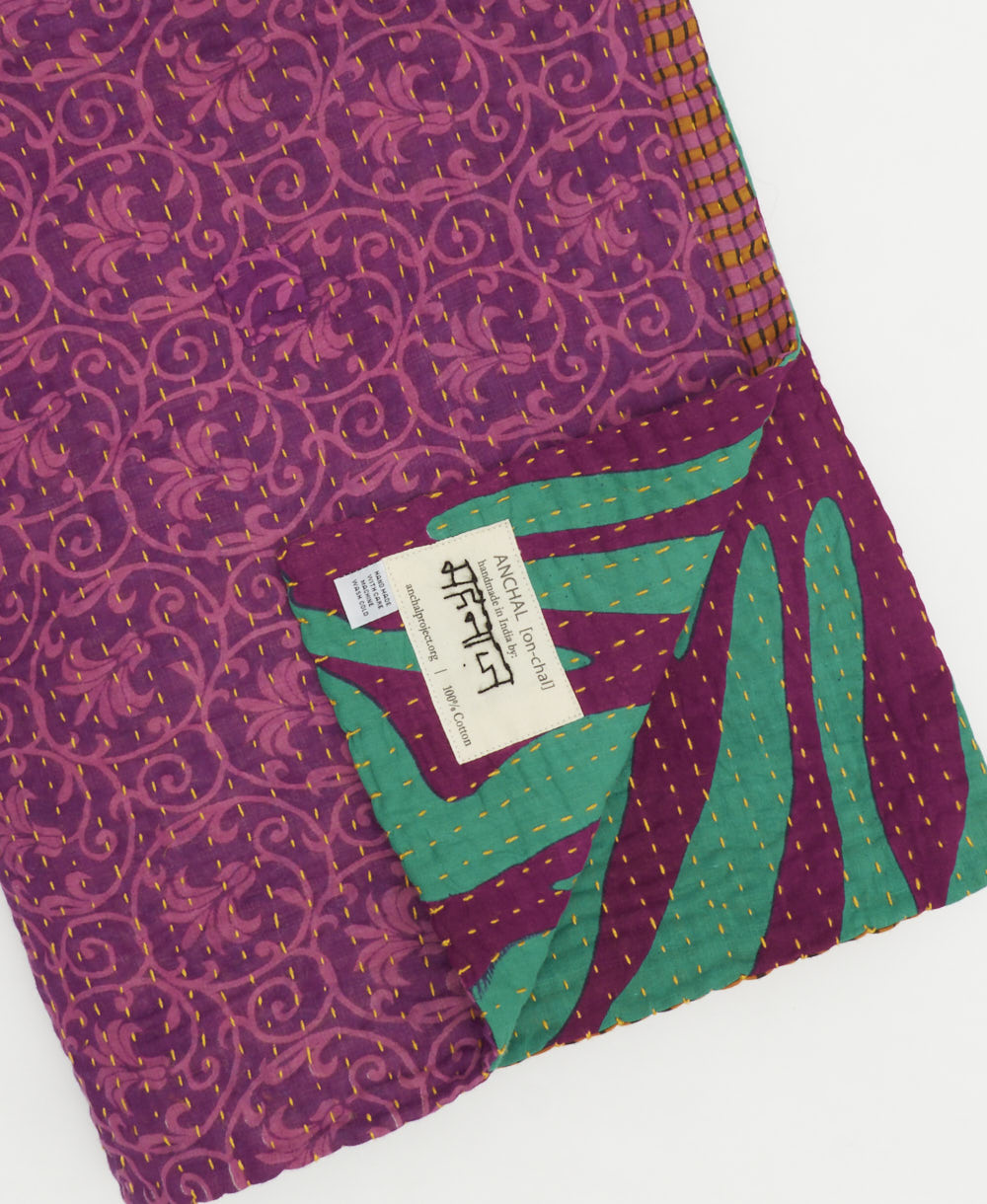 kantha quilt throw with a tag featuring the hand-stitched signature of the maker