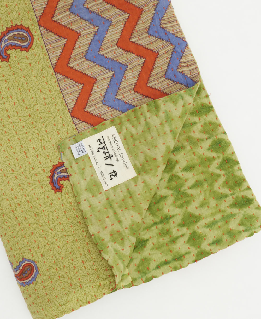 kantha quilt throw with a tag featuring the hand-stitched signature of the maker