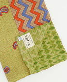 kantha quilt throw with a tag featuring the hand-stitched signature of the maker