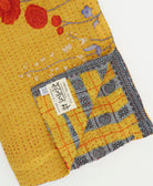 kantha quilt throw with a tag featuring the hand-stitched signature of the maker