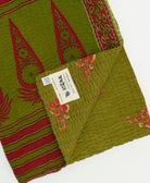 kantha quilt throw with a tag featuring the hand-stitched signature of the maker