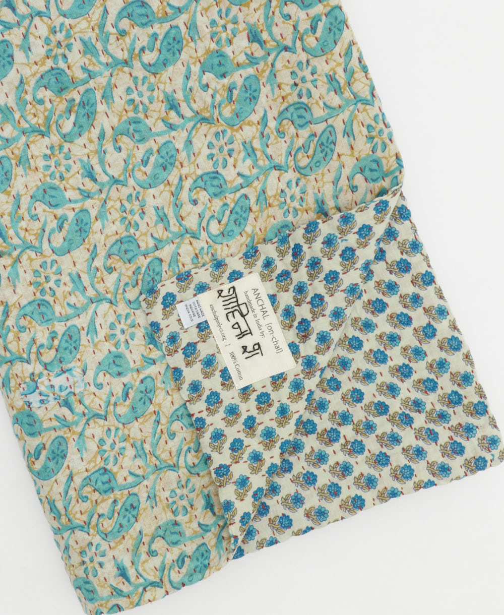 kantha quilt throw with a tag featuring the hand-stitched signature of the maker