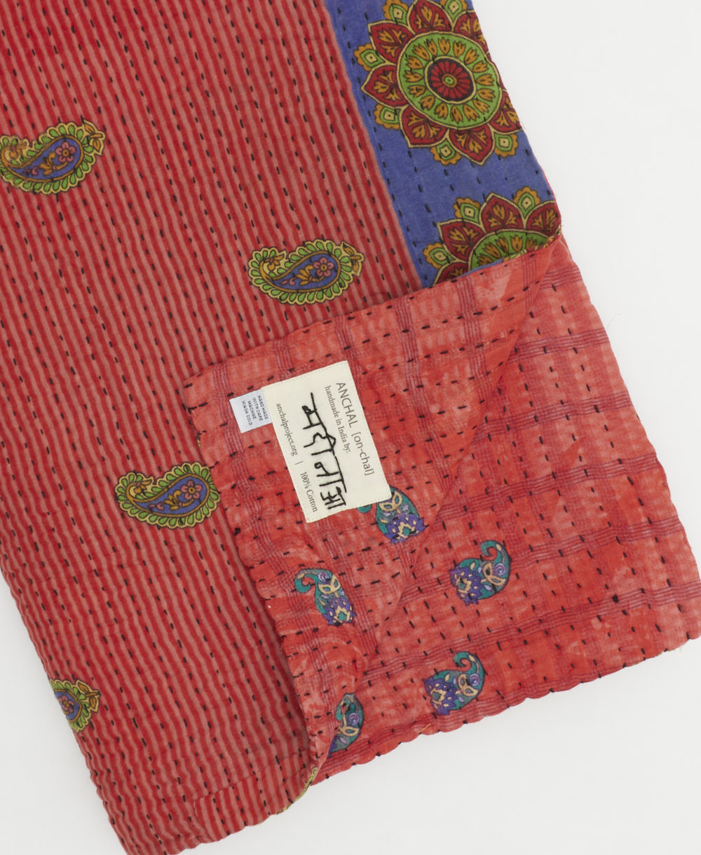 kantha quilt throw with a tag featuring the hand-stitched signature of the maker