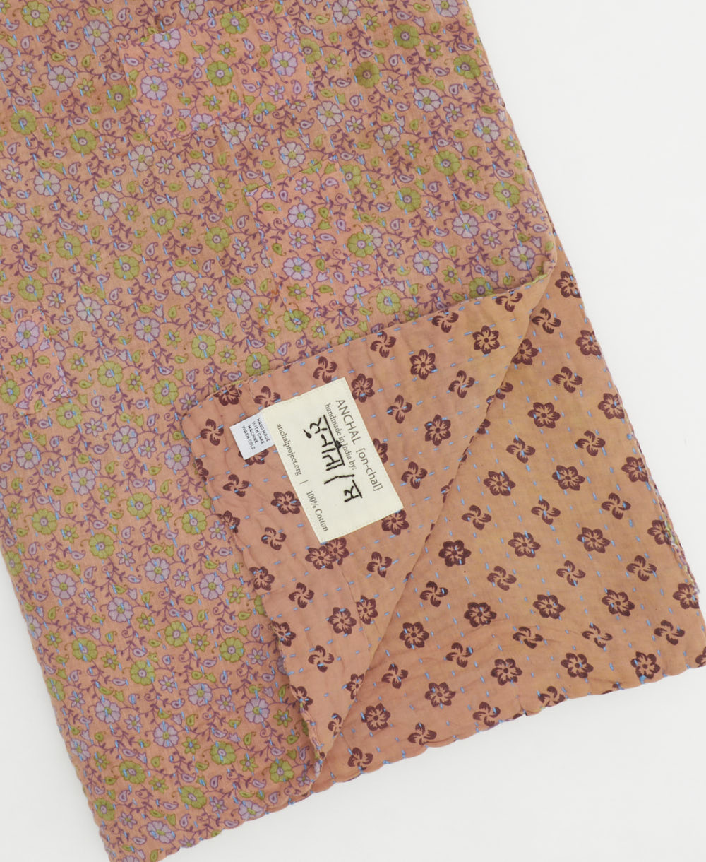 kantha quilt throw with a tag featuring the hand-stitched signature of the maker