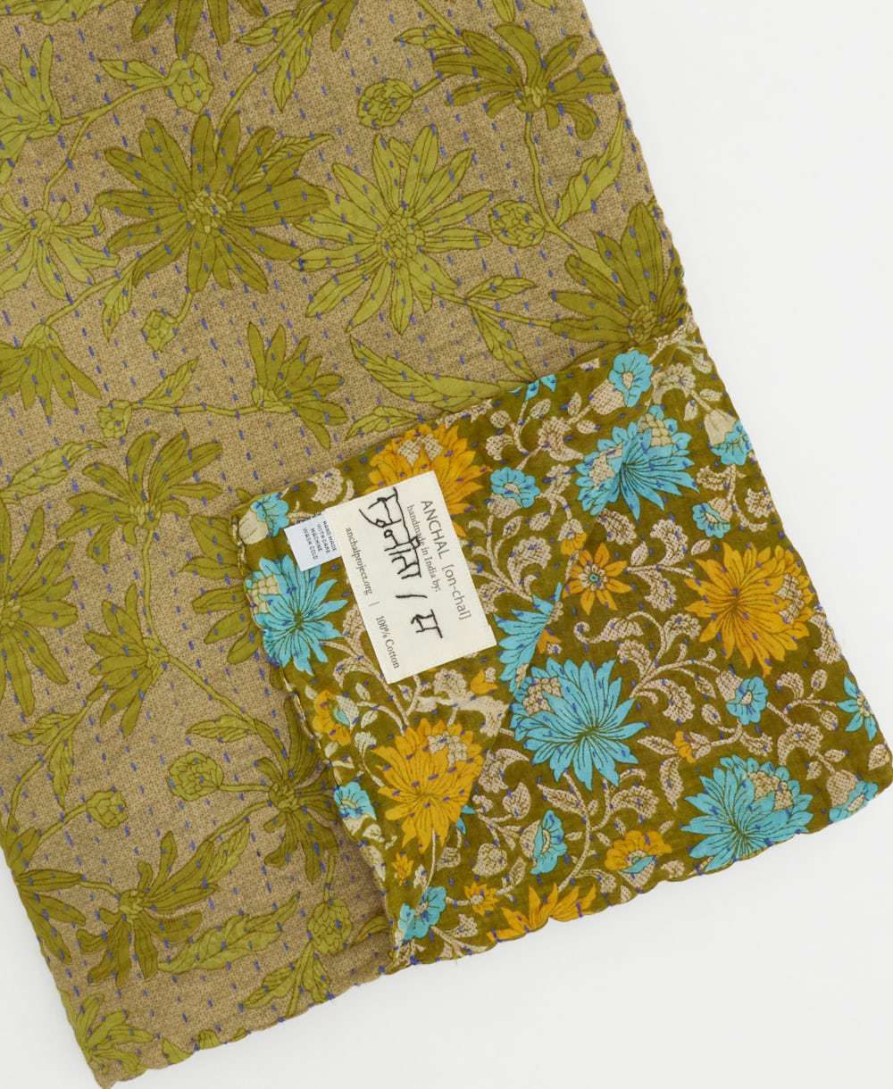 kantha quilt throw with a tag featuring the hand-stitched signature of the maker