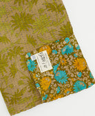 kantha quilt throw with a tag featuring the hand-stitched signature of the maker