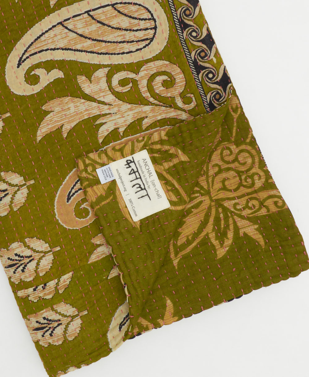 kantha quilt throw with a tag featuring the hand-stitched signature of the maker