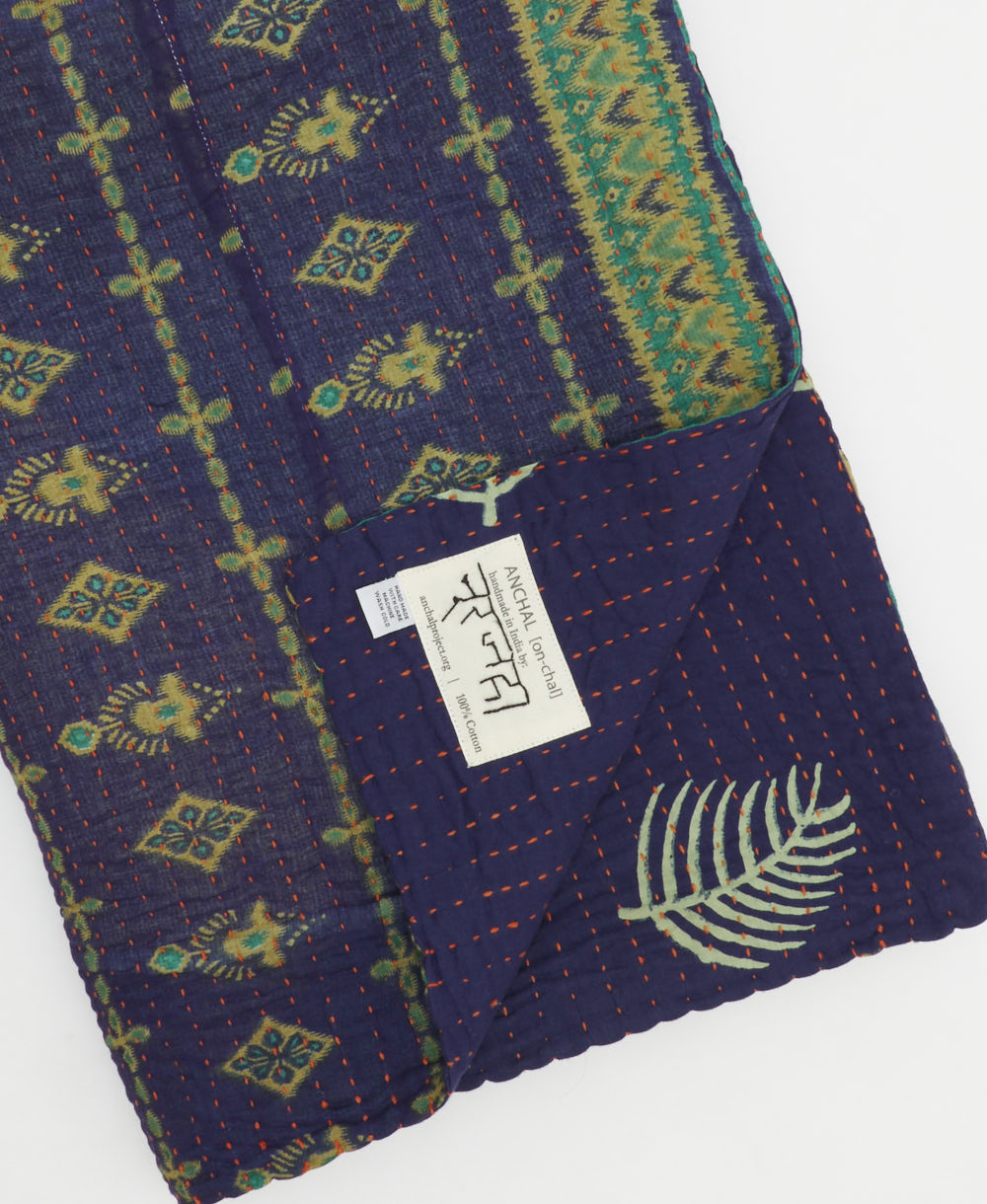 kantha quilt throw with a tag featuring the hand-stitched signature of the maker