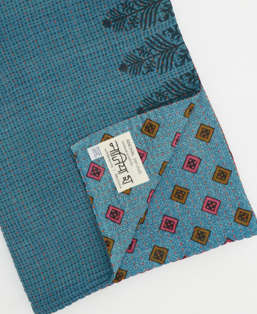 kantha quilt throw with a tag featuring the hand-stitched signature of the maker