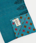 kantha quilt throw with a tag featuring the hand-stitched signature of the maker
