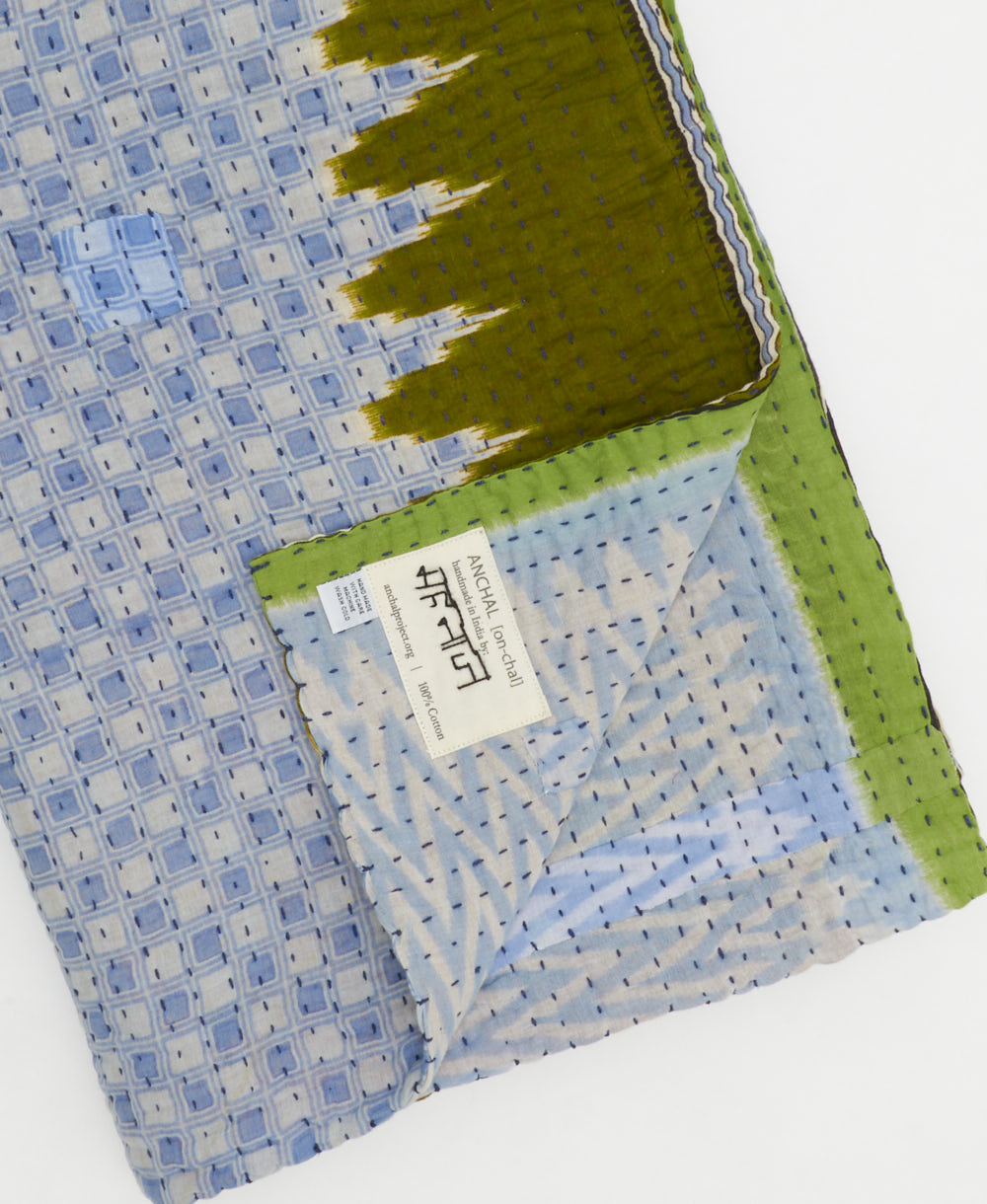 kantha quilt throw with a tag featuring the hand-stitched signature of the maker