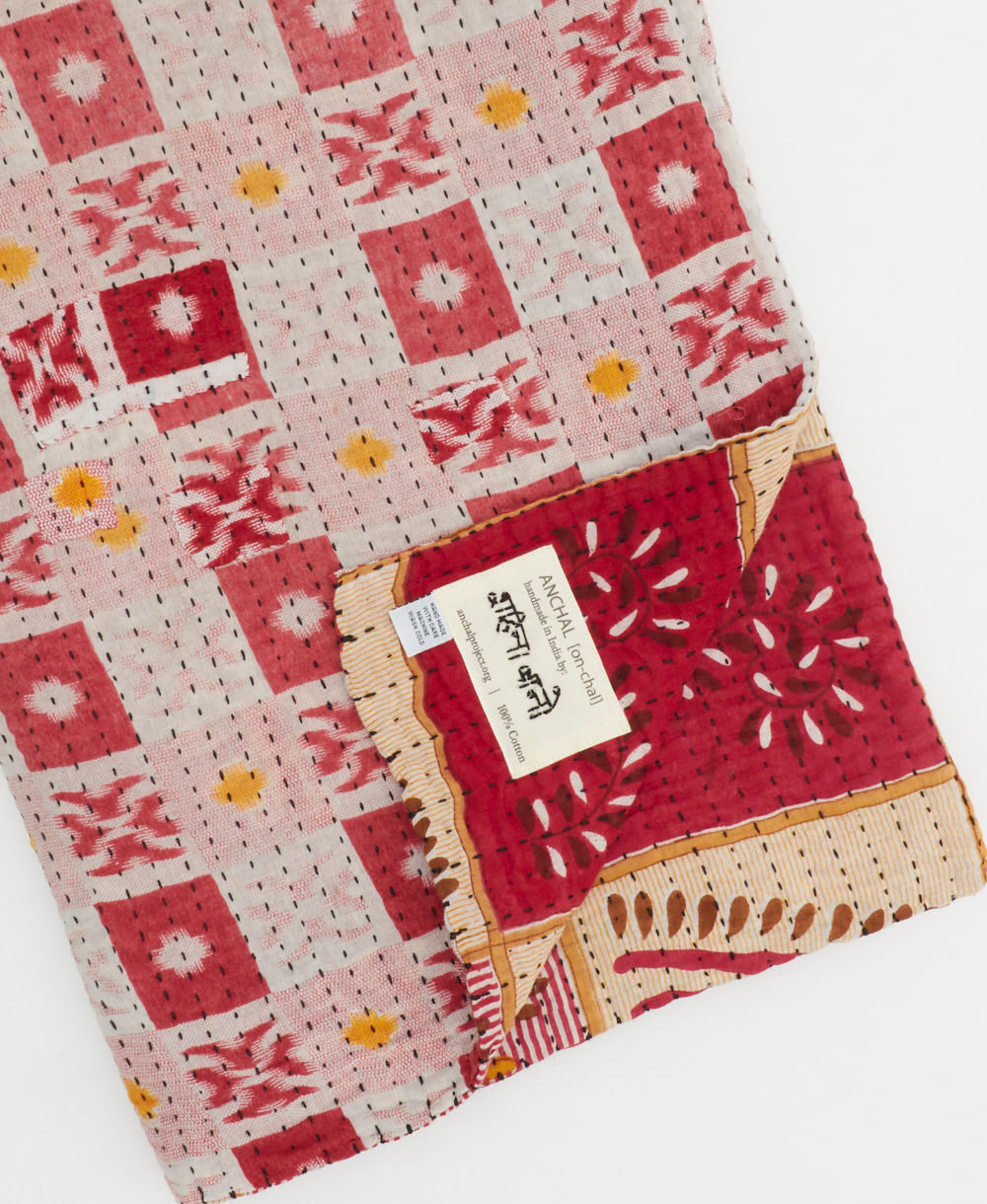 kantha quilt throw with a tag featuring the hand-stitched signature of the maker