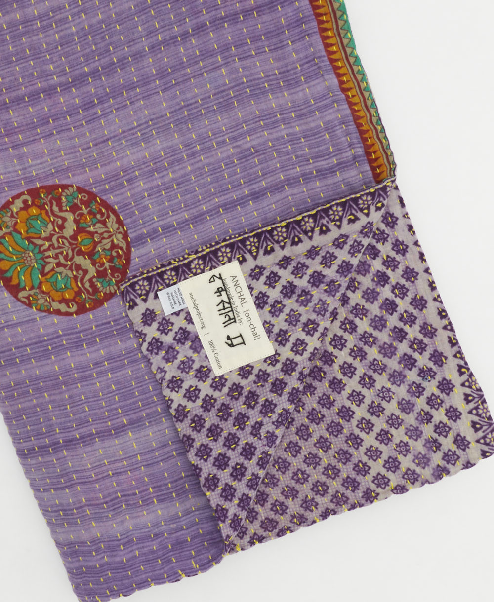 kantha quilt throw with a tag featuring the hand-stitched signature of the maker