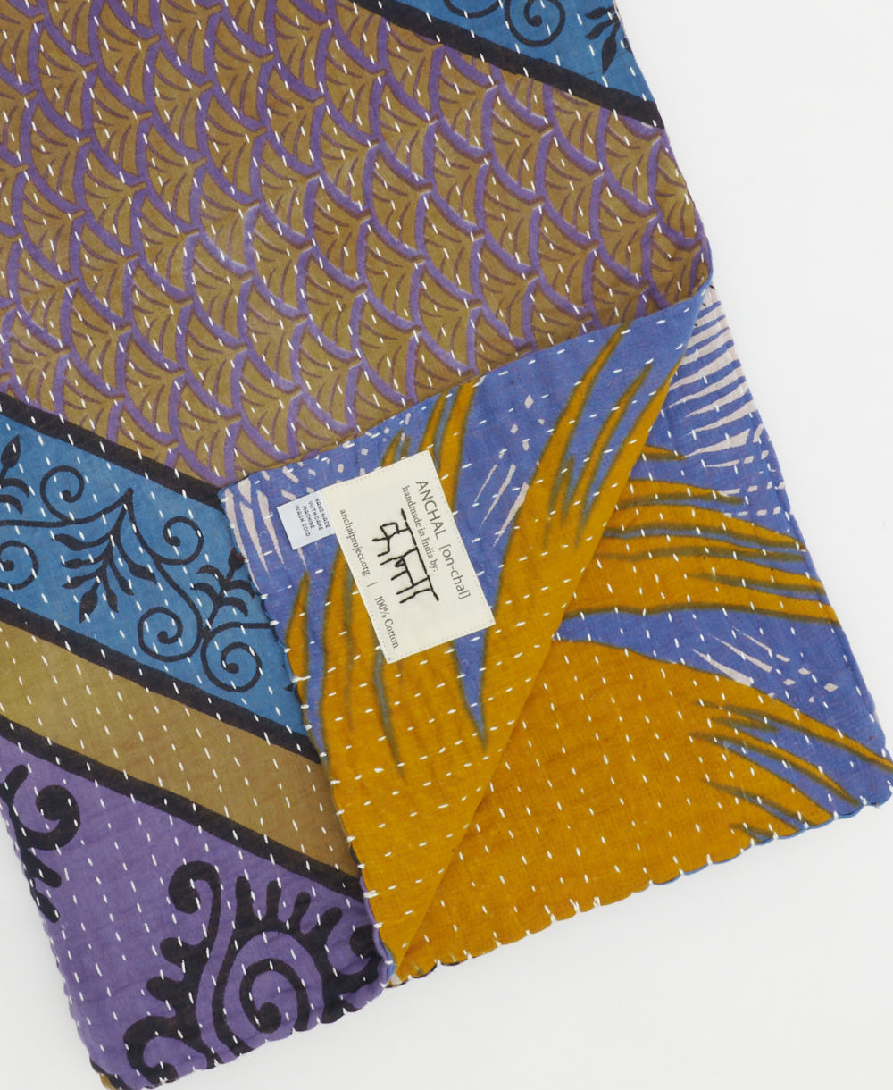 kantha quilt throw with a tag featuring the hand-stitched signature of the maker