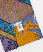 kantha quilt throw with a tag featuring the hand-stitched signature of the maker