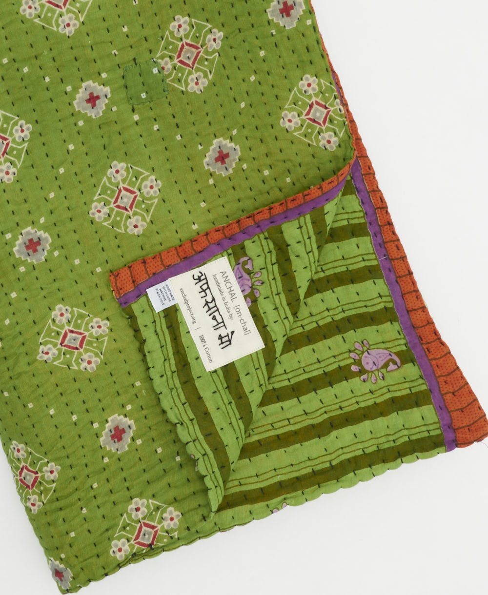 kantha quilt throw with a tag featuring the hand-stitched signature of the maker