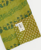 kantha quilt throw with a tag featuring the hand-stitched signature of the maker