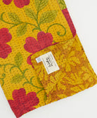 kantha quilt throw with a tag featuring the hand-stitched signature of the maker