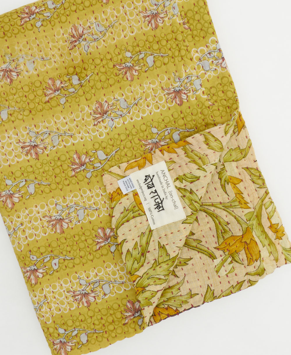 kantha quilt throw with a tag featuring the hand-stitched signature of the maker