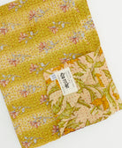 kantha quilt throw with a tag featuring the hand-stitched signature of the maker