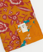 kantha quilt throw with a tag featuring the hand-stitched signature of the maker