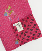 kantha quilt throw with a tag featuring the hand-stitched signature of the maker
