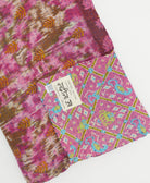kantha quilt throw with a tag featuring the hand-stitched signature of the maker